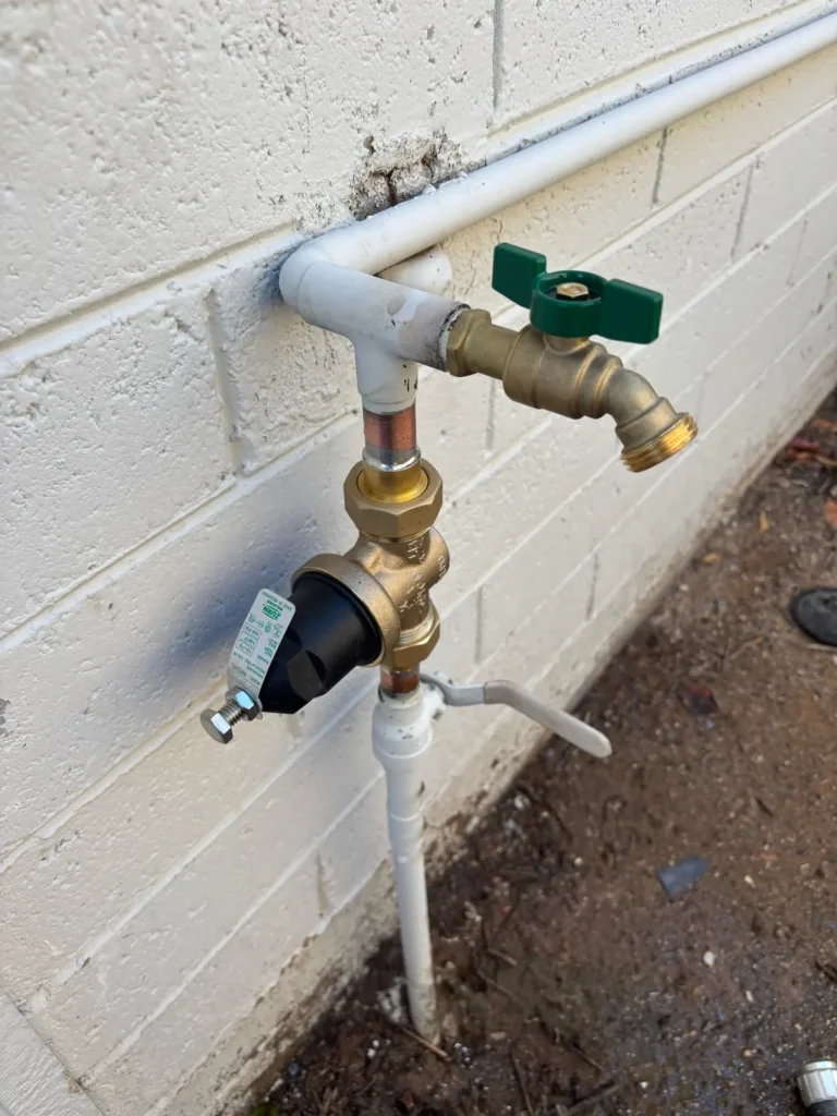 New outdoor hose bib and pressure regulator installed on a block wall